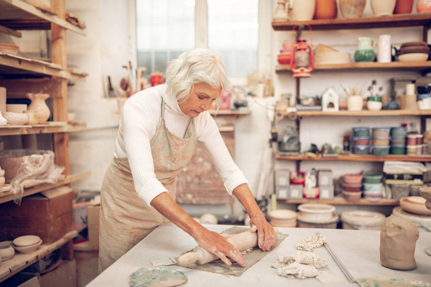 Ευχάριστη ηλικιωμένη γυναίκα κοιτάζοντας τη δουλειά της - Φωτογραφία, εικόνα
