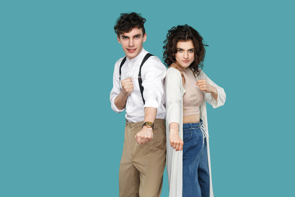 two funny brunette stylish partners standing with boxing fists and looking at camera with smile on blue background - Zdjęcie, obraz