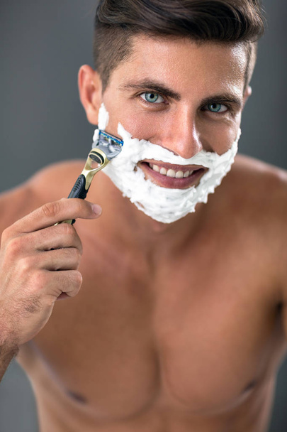 young man passing the razor for the beard while it looks at the  - Φωτογραφία, εικόνα