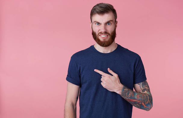 Jovem atraente cara de barba vermelha com olhos azuis parece indignado
,  - Foto, Imagem