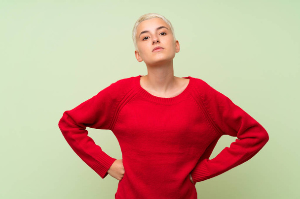 Teenager girl with white short hair over green wall angry - Photo, Image