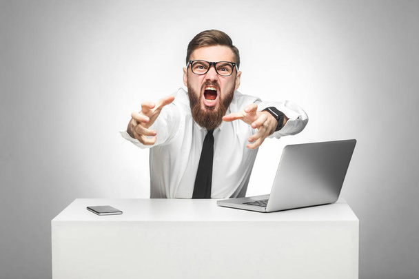 aggressive angry young businessman in white shirt and black tie are screaming and showing strangle gesture on grey background - Photo, image