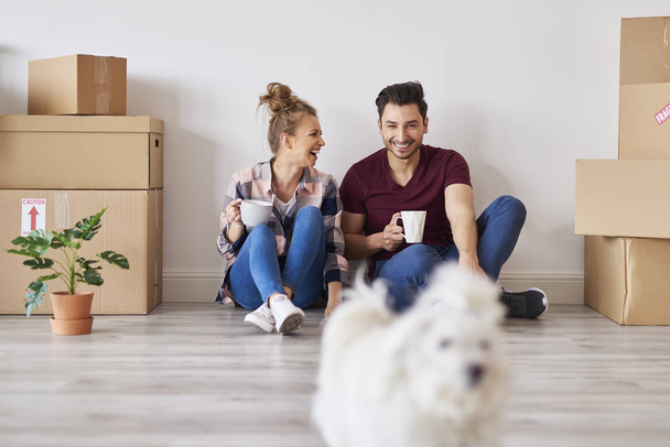 fröhliches Paar mit Kaffeetassen entspannt in seiner neuen Wohnung - Foto, Bild
