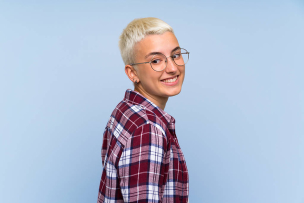 Adolescente avec les cheveux courts blancs sur le mur bleu riant
 - Photo, image