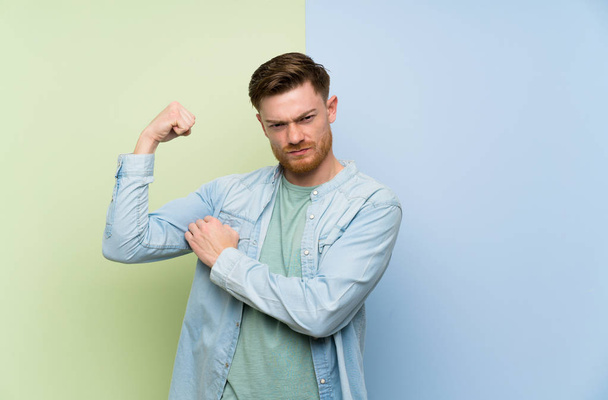 Redhead man over colorful background doing strong gesture - Foto, Imagem