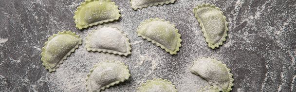 panoramic shot of green raw ravioli with flour on grey table - Photo, Image