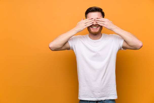 Redhead man over brown wall covering eyes by hands - Photo, Image