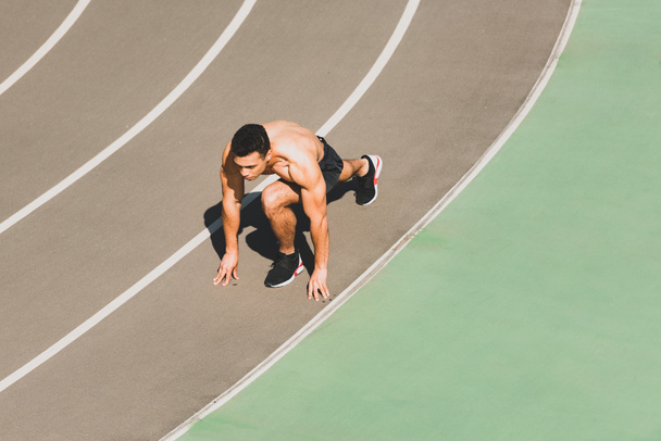 mixed race sportsman preparing to run at stadium - Фото, зображення