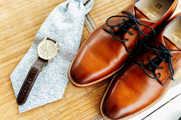 Close-up van de bruidegom schoenen, horloges en gelijkspel. Klaar. lichte achtergrond - Foto, afbeelding