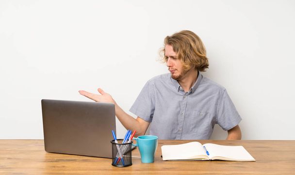 Hombre rubio con un portátil con copyspace con dudas
 - Foto, Imagen