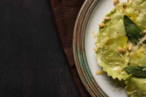 close up view of delicious green ravioli with sage, cheese and pine nuts served in vintage plate - Fotoğraf, Görsel