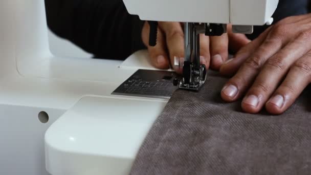 ミシンの後ろに布を持つ男性の縫い目の手。繊維および衣類のための糸の縫い生地が付いている針。アトリエでミシンの作業プロセスをクローズアップ。繊維産業製造業 - 映像、動画