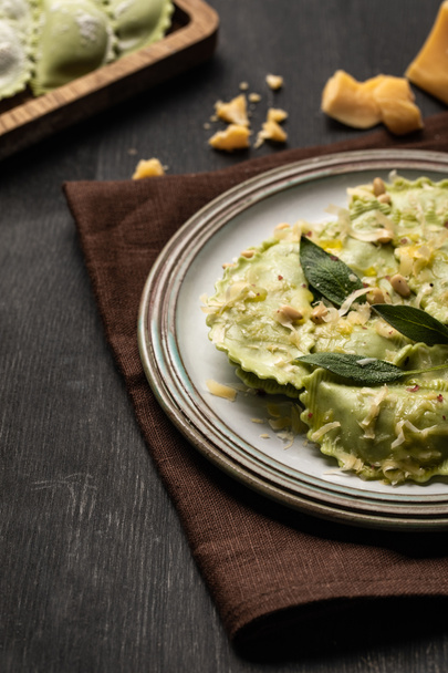 Nahaufnahme von grünen Ravioli mit geschmolzenem Käse, Pinienkernen und grünen Salbeiblättern im Retro-Teller  - Foto, Bild