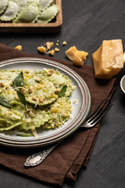 おいしい緑のイタリアンラビオリと松の実、セージ、溶かしたチーズがテーブルの上に出される - 写真・画像