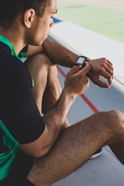 обрізаний вид змішаної гонки спортсмен, використовуючи смарт-годинник на стадіоні
 - Фото, зображення