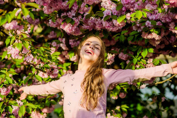 Capturing a happy moment. Natural cosmetics for skin. happy girl in cherry flower. Sakura tree blooming. small girl child in spring flower bloom. summer. Childhood beauty. blossom smell, allergy - Photo, image