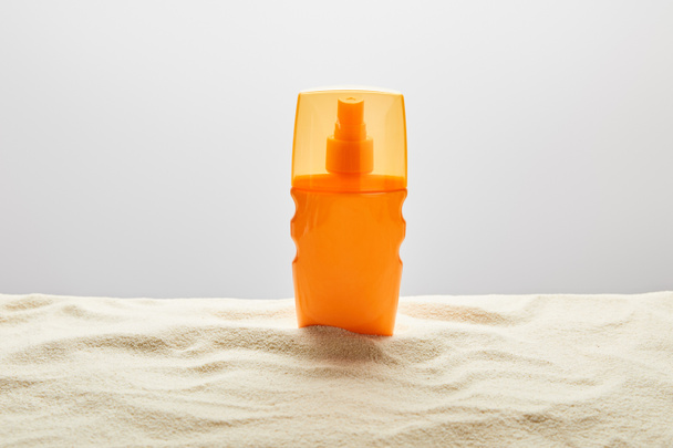 sunscreen in orange bottle on textured sand on grey background - Photo, Image