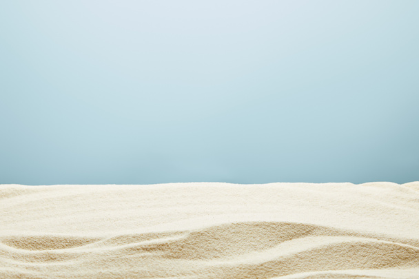 golvende getextureerde goudkleurig zand op blauwe achtergrond - Foto, afbeelding
