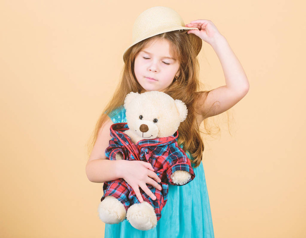 Small girl straw hat hold teddy bear plush toy. In love with cute teddy bear. Happy childhood. Tender attachments. Kid little girl carefully hug soft toy teddy bear beige background. Cutest ever - 写真・画像