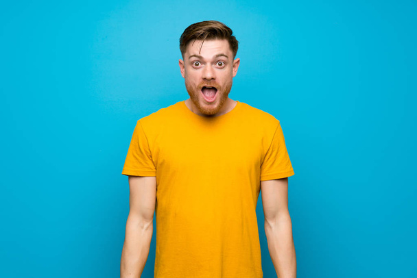 Redhead man over blue wall with surprise facial expression - Photo, Image
