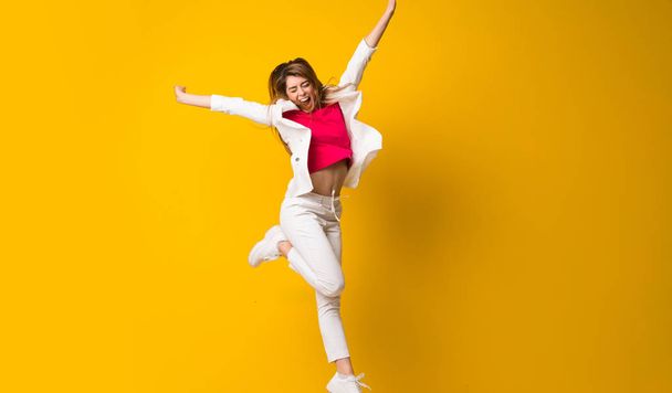 Young woman jumping over isolated yellow wall - Fotografie, Obrázek