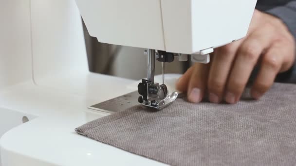 ミシンの後ろに布を持つ男性の縫い目の手。繊維および衣類のための糸の縫い生地が付いている針。アトリエでミシンの作業プロセスをクローズアップ。繊維産業製造業 - 映像、動画