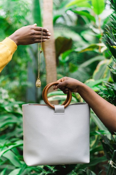 schwarze Mädchen halten eine Tasche und Dekoration in der Hand. Grüner Hintergrund im Dschungel. - Foto, Bild