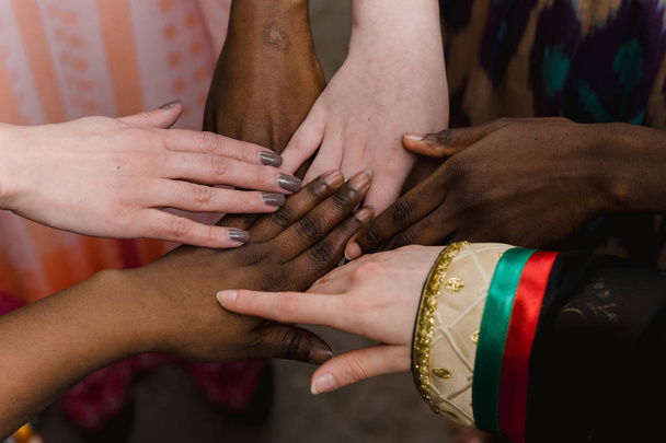 Mãos de um grupo feliz de pessoas de diferentes nacionalidades que ficam juntas em um círculo de felizes. Uma equipe de pessoas de africanos, brasileiros, jordanianos, europeus, brancos, negros, indianos
. - Foto, Imagem