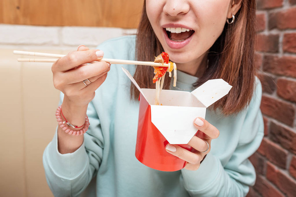 Nainen syö wok nuudeleita aasialaisessa ravintolassa
 - Valokuva, kuva