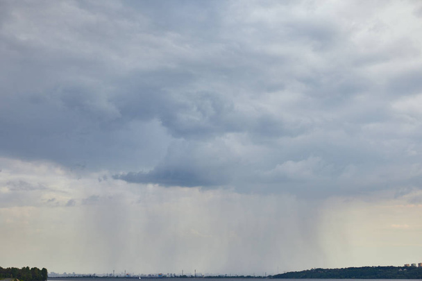 vista nublada de nubes azules y lluvia sobre la costa forestal
 - Foto, imagen