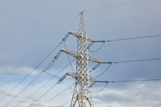 az elektromos pólus nézete a hosszú huzalokkal a szürke égbolt háttérben - Fotó, kép