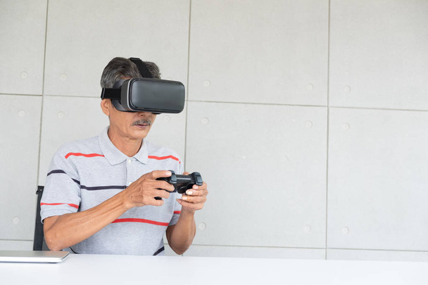 Vieil homme en réalité vr lunettes de réalité virtuelle avec manette de jeu, homme âgé profiter et heureux en vacances
. - Photo, image
