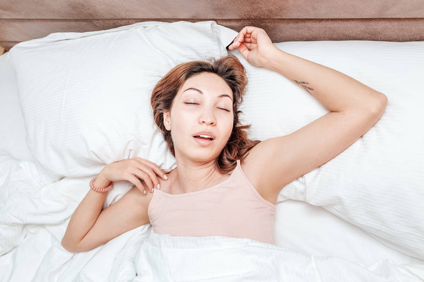 Ασιατικές γυναίκα κοιμάται χαλαρή σε ένα μεγάλο ευρύχωρο κρεβάτι στο σπίτι ή σε ένα ξενοδοχείο - Φωτογραφία, εικόνα