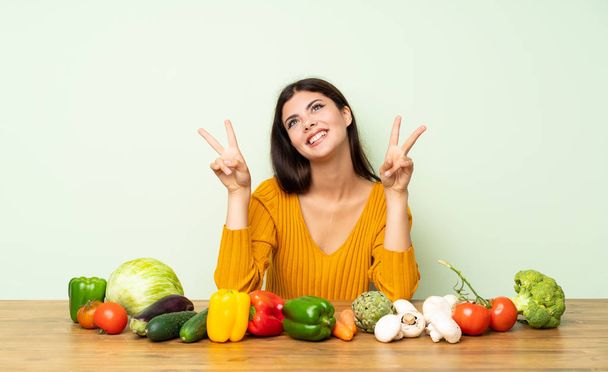 Подросток с большим количеством овощей показывает знак победы обеими руками
 - Фото, изображение