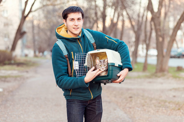 Mann mit Hauskatze im Tragetuch auf der Straße unterwegs - Foto, Bild