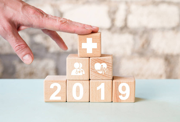 Arts hand regelen hout blok stapelen met pictogram 2019 jaar gezondheidszorg medische, verzekering voor uw gezondheid concept. - Foto, afbeelding