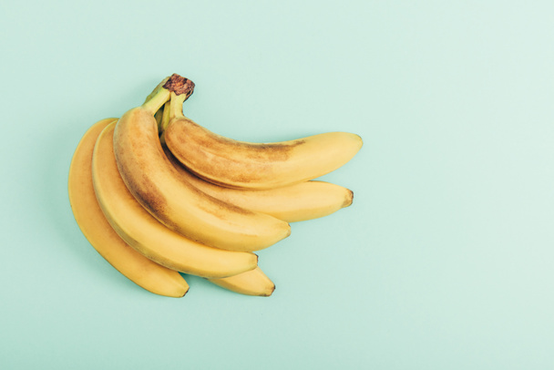 Top view of ripe bunch of bright bananas on turquoise background - Fotografie, Obrázek