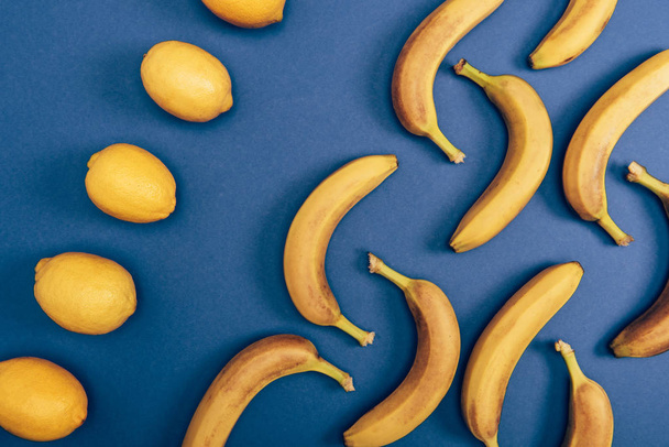 Top view of juicy and yellow lemons and bright bananas on blue background - Foto, immagini