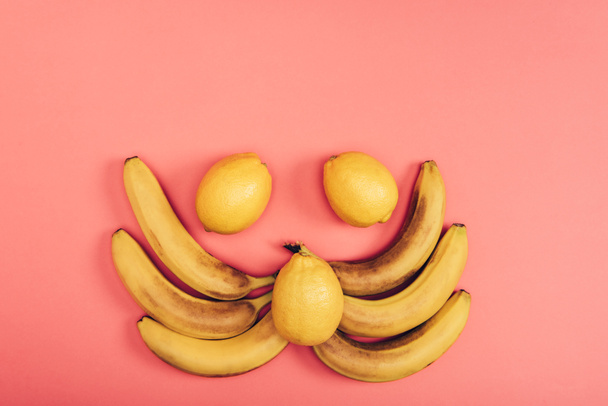 Flat lay with food composition of yellow juicy bananas and fresh lemons on coral background - Fotoğraf, Görsel