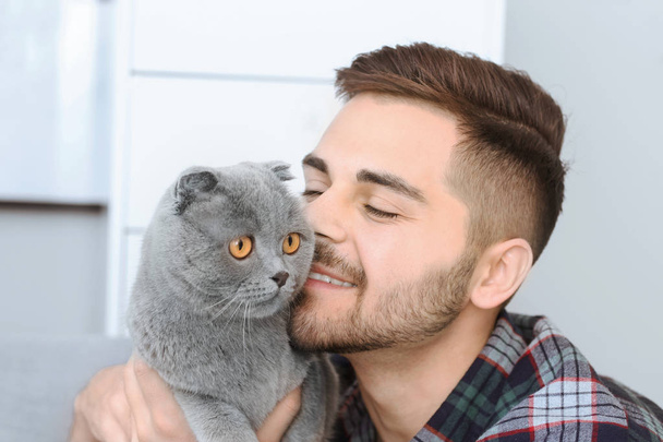 Jeune homme avec chat drôle mignon à la maison
 - Photo, image