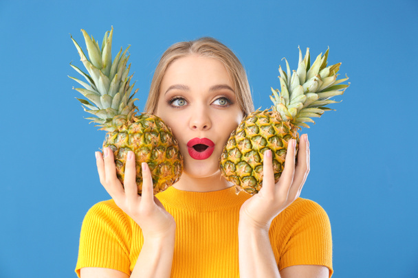 Beautiful young woman with pineapples on color background - Photo, Image