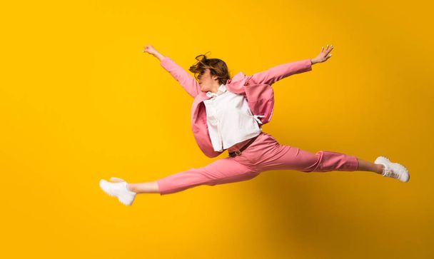 Young woman jumping over isolated yellow wall - Photo, image