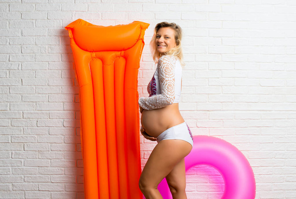 Ξανθιά έγκυος γυναίκα με μαγιό για τις καλοκαιρινές διακοπές - Φωτογραφία, εικόνα