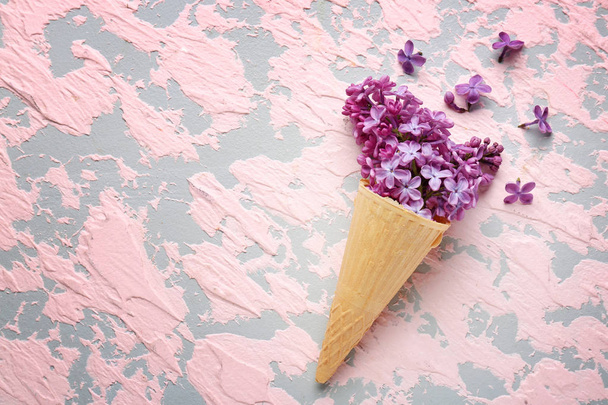 Waffle cone with beautiful lilac flowers on color background - Φωτογραφία, εικόνα