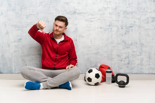 Uomo rosso sport mostrando pollice verso il basso con espressione negativa
 - Foto, immagini