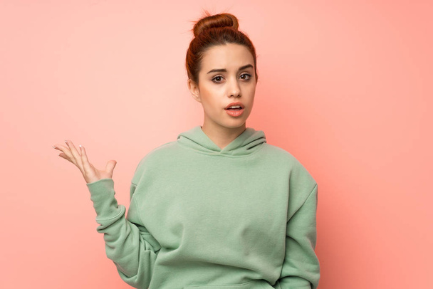 Young redhead woman with sweatshirt making doubts gesture - Photo, Image