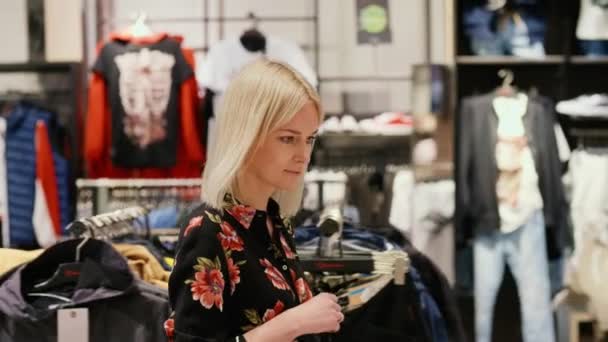 Mujer joven durante las grandes compras en la tienda de ropa
 - Metraje, vídeo