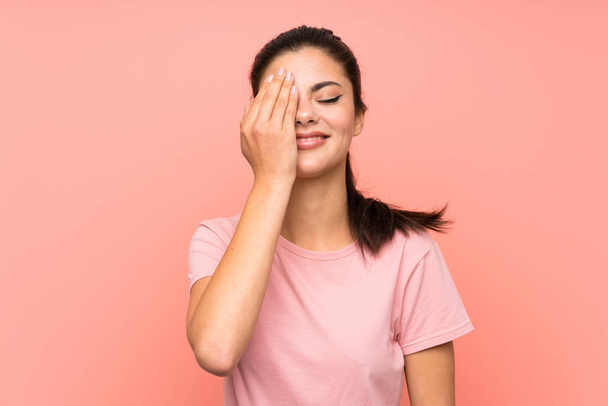 Teenager girl over isolated pink background covering a eye by hand - Fotografie, Obrázek