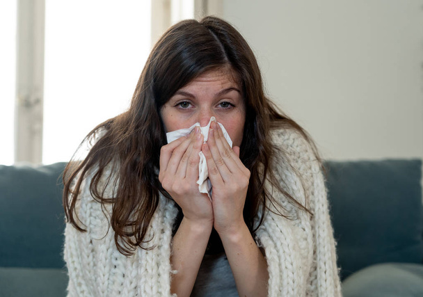 Sick woman on sofa sneezing and blowing her nose with allergy, hay fever or cold feeling unwell, fatigue and restless not being able to go to work. Lifestyle portrait In Health Care and medical. - Photo, Image