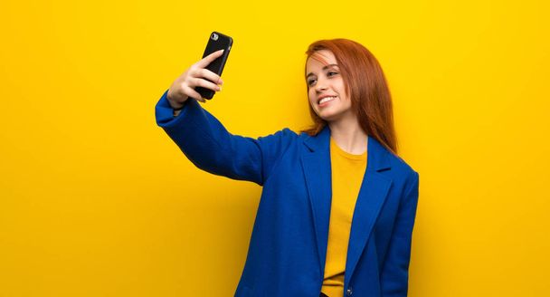 Giovane donna rossa con trench fare un selfie
 - Foto, immagini